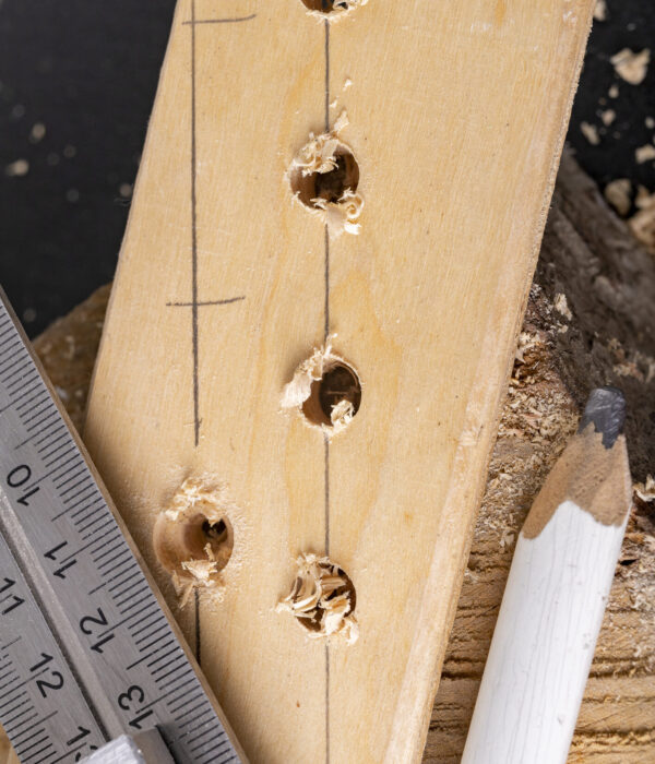Marking drill points on a piece of wood. Minor carpentry work in the workshop. Dark background.